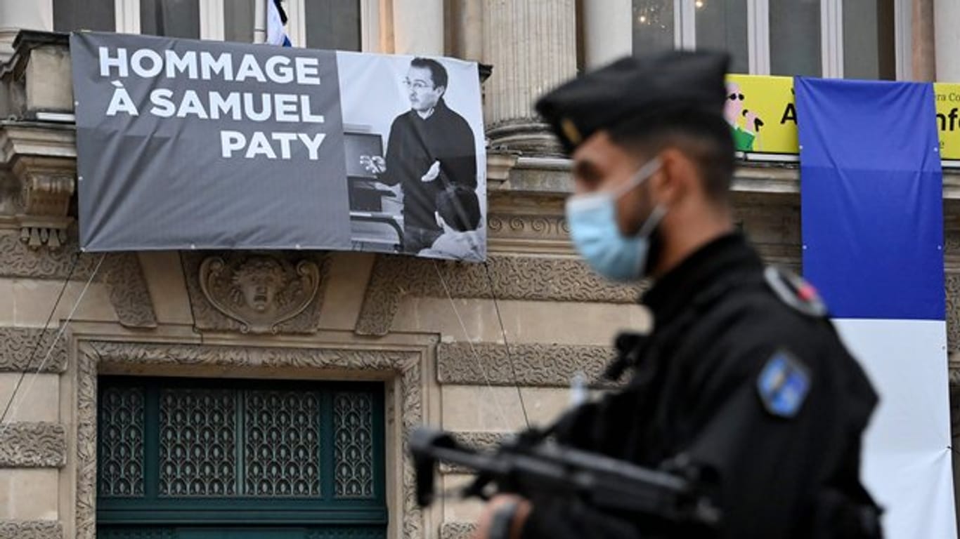 Ein Polizist steht neben der Opera Comedie in Montpellier, an deren Fassade eine Hommage an den enthaupteten Lehrer Samuel Paty angebracht ist.