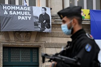 Ein Polizist steht neben der Opera Comedie in Montpellier, an deren Fassade eine Hommage an den enthaupteten Lehrer Samuel Paty angebracht ist.