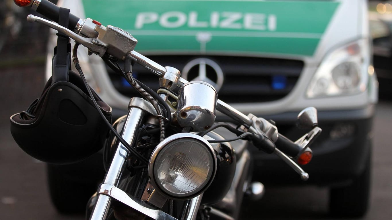 Ein Motorrad steht vor einem Polizeiauto (Symbolbild): In Hagen sind mehrere mutmaßliche Rocker der "Bandidos" angeklagt.