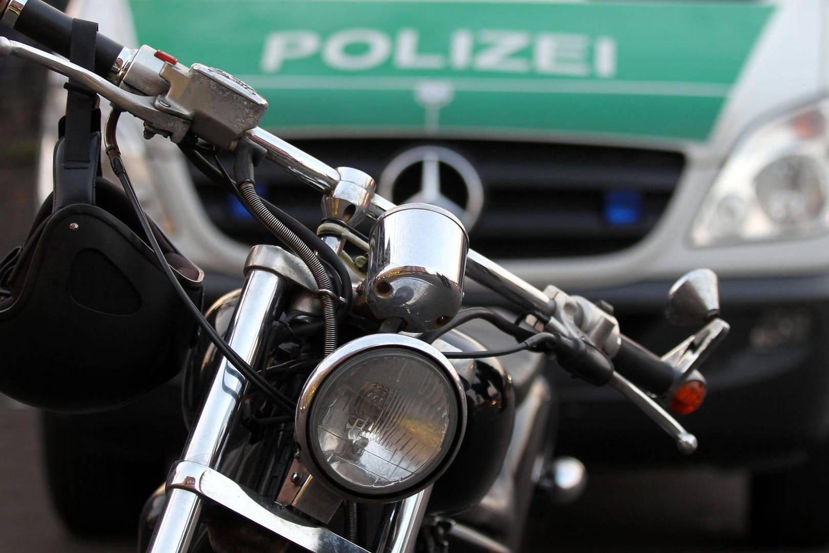 Ein Motorrad steht vor einem Polizeiauto (Symbolbild): In Hagen sind mehrere mutmaßliche Rocker der "Bandidos" angeklagt.