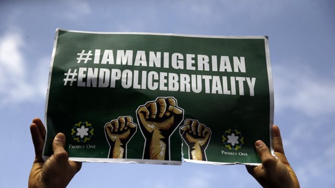 Menschen demonstrieren in Lagos mit Transparenten auf der Straße gegen die Brutalität der Polizei.