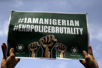 Menschen demonstrieren in Lagos mit Transparenten auf der Straße gegen die Brutalität der Polizei.