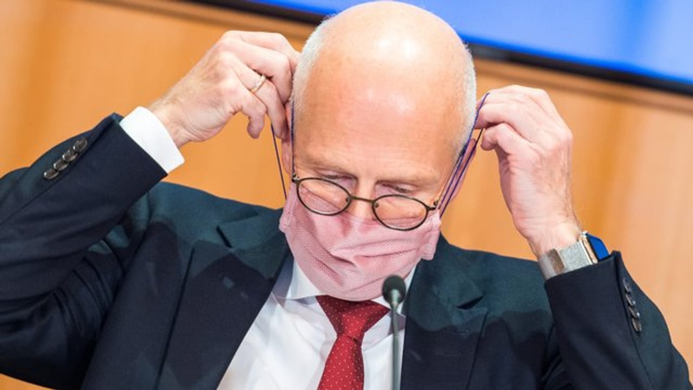 Peter Tschentscher (SPD) setzt sich seine Maske auf