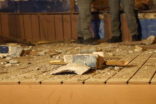 Isreaelische Polizisten stehen nach einem Raketenangriff aus dem Gazastreifen neben einer beschädigten Mauer.
