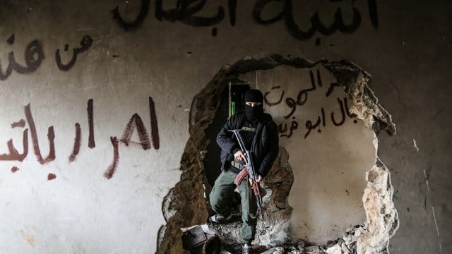 Ein bewaffneter Kämpfer der Miliz Haiat Tahrir al-Scham inspiziert ein beschädigtes Haus. Ein bewaffneter Kämpfer der Miliz Haiat Tahrir al-Scham inspiziert ein beschädigtes Haus.