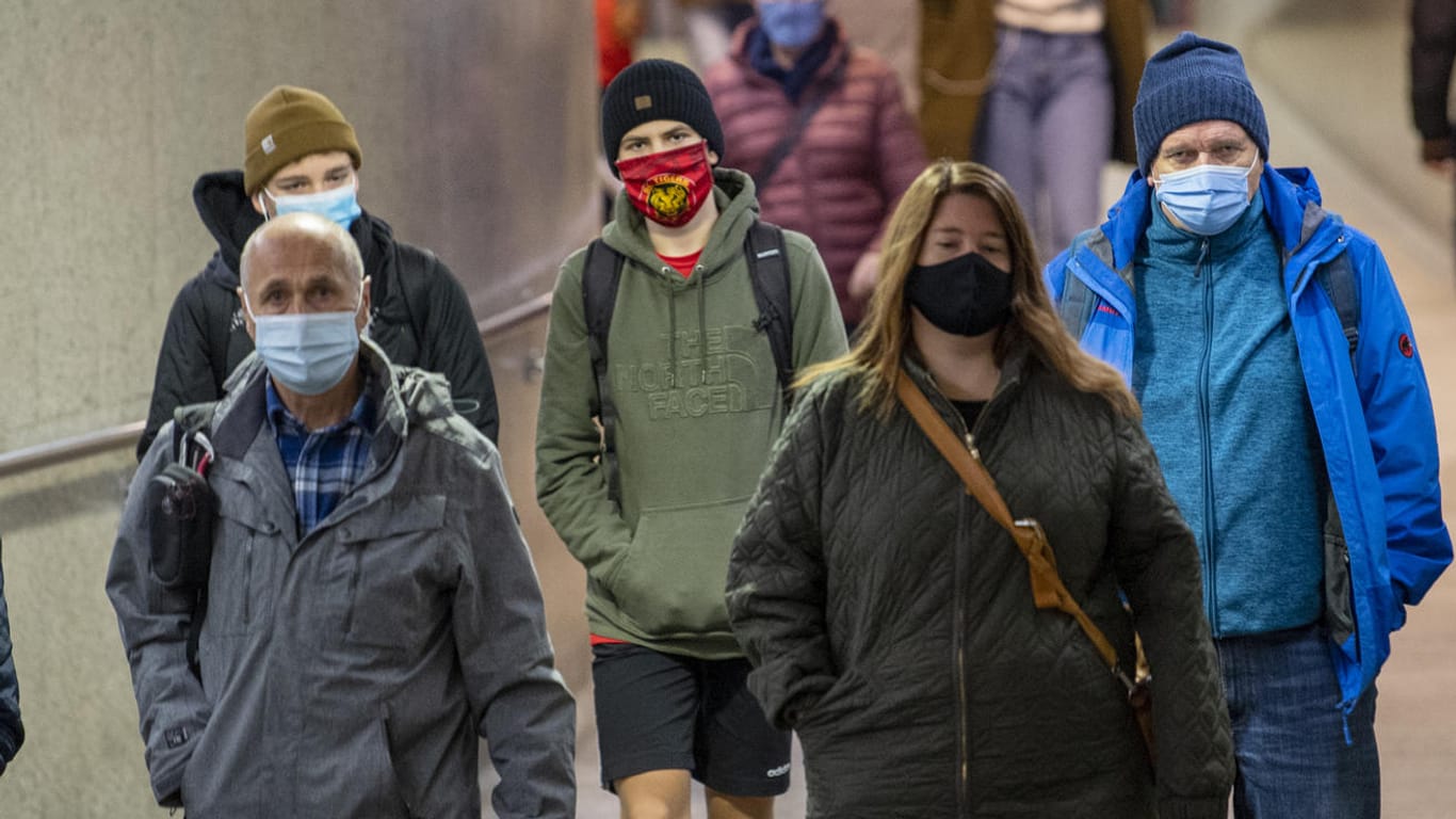Passanten tragen auf einem Bahnhof Masken: Ärtzekammerpräsident Reinhardt hat die Wirksamkeit von Masken angezweifelt.