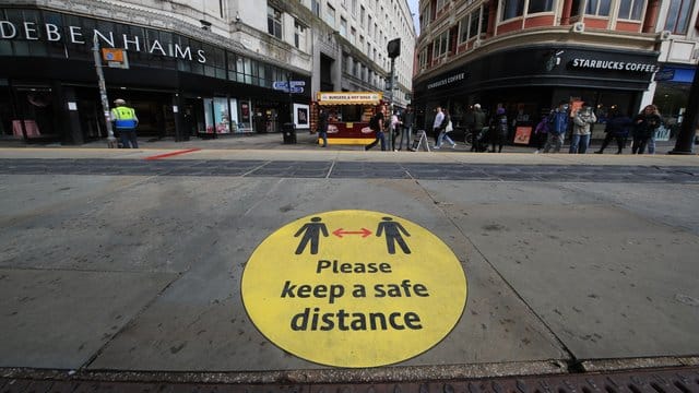 Ein Leitschild auf dem Bürgersteig weist in Manchester auf die Beachtung der Mindestabstände hin. Ein Leitschild auf dem Bürgersteig weist in Manchester auf die Beachtung der Mindestabstände hin.