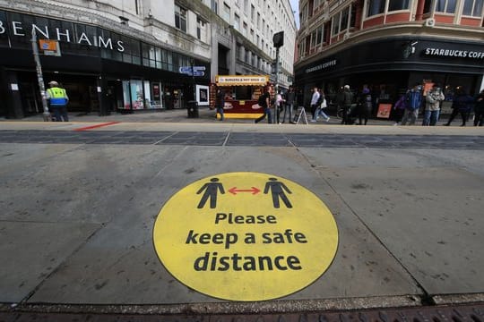 Ein Leitschild auf dem Bürgersteig weist in Manchester auf die Beachtung der Mindestabstände hin.
