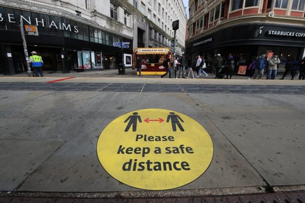 Ein Leitschild auf dem Bürgersteig weist in Manchester auf die Beachtung der Mindestabstände hin.