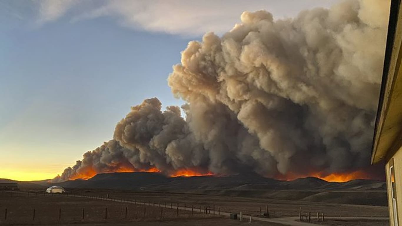 Hinter einem Bergkamm im Norden von Colorado steigen über dem Schein des Feuers die Rauchwolken auf.