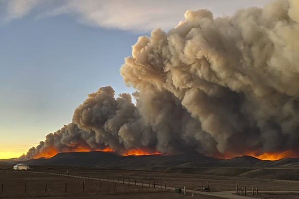 Hinter einem Bergkamm im Norden von Colorado steigen über dem Schein des Feuers die Rauchwolken auf.