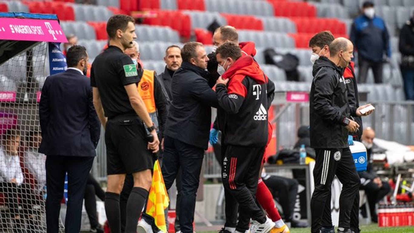 Bayern-Trainer Hansi Flick spricht mit Alphonso Davies bei der verletzungsbedingten Auswechslung.