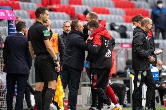 Bayern-Trainer Hansi Flick spricht mit Alphonso Davies bei der verletzungsbedingten Auswechslung.