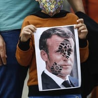 Ein Kind hält in Istanbul ein mit einem Schuhabdruck versehenes Foto von Emmanuel Macron in die Kamera: Der französische Präsident ist unter Beschuss.