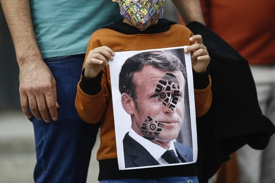 Ein Kind hält in Istanbul ein mit einem Schuhabdruck versehenes Foto von Emmanuel Macron in die Kamera: Der französische Präsident ist unter Beschuss.