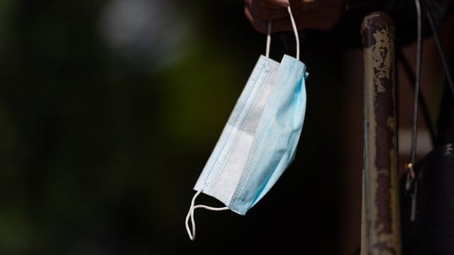 Ein Frau hält einen Mund-Nasen-Schutz in der Hand Ein Frau hält einen Mund-Nasen-Schutz in der Hand