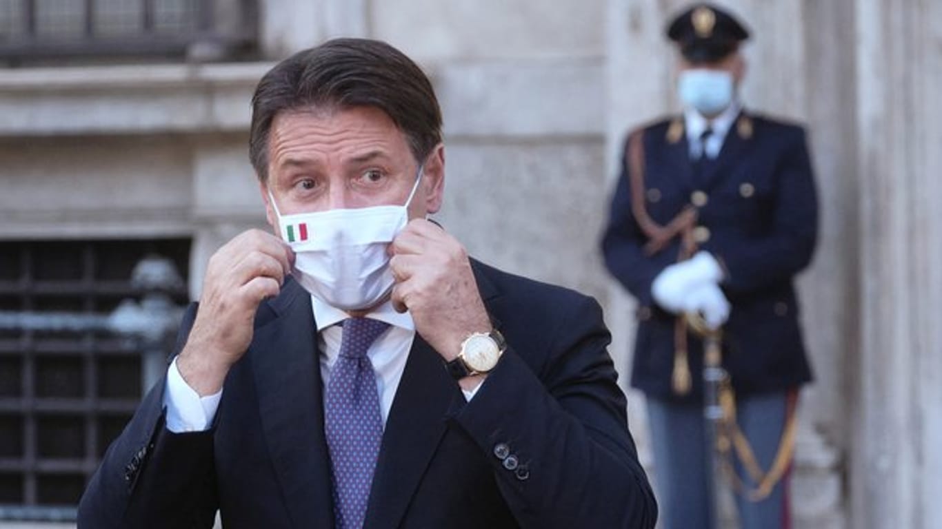 Giuseppe Conte, Ministerpräsident von Italien, richtet seinen Mund-Nasen-Schutz bei einer Pressekonferenz.