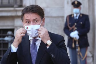 Giuseppe Conte, Ministerpräsident von Italien, richtet seinen Mund-Nasen-Schutz bei einer Pressekonferenz.
