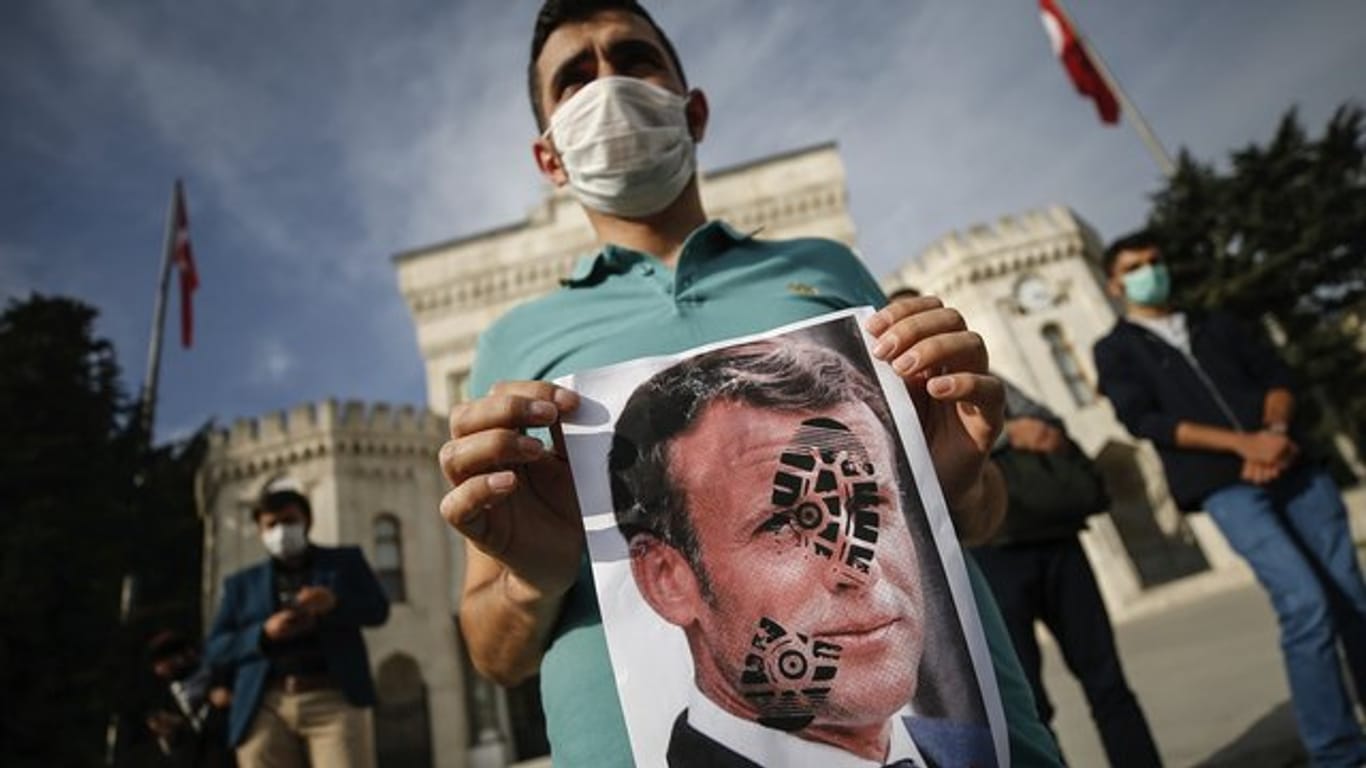 Ein junger Mann hält in Istanbul ein mit einem Schuhabdruck versehenes Foto von Emmanuel Macron in die Kamera.