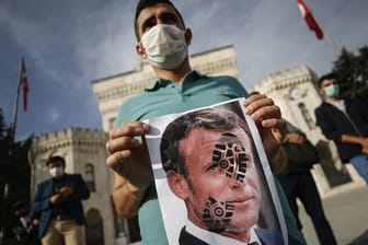 Ein junger Mann hält in Istanbul ein mit einem Schuhabdruck versehenes Foto von Emmanuel Macron in die Kamera.