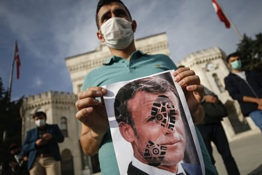 Ein junger Mann hält in Istanbul ein mit einem Schuhabdruck versehenes Foto von Emmanuel Macron in die Kamera.