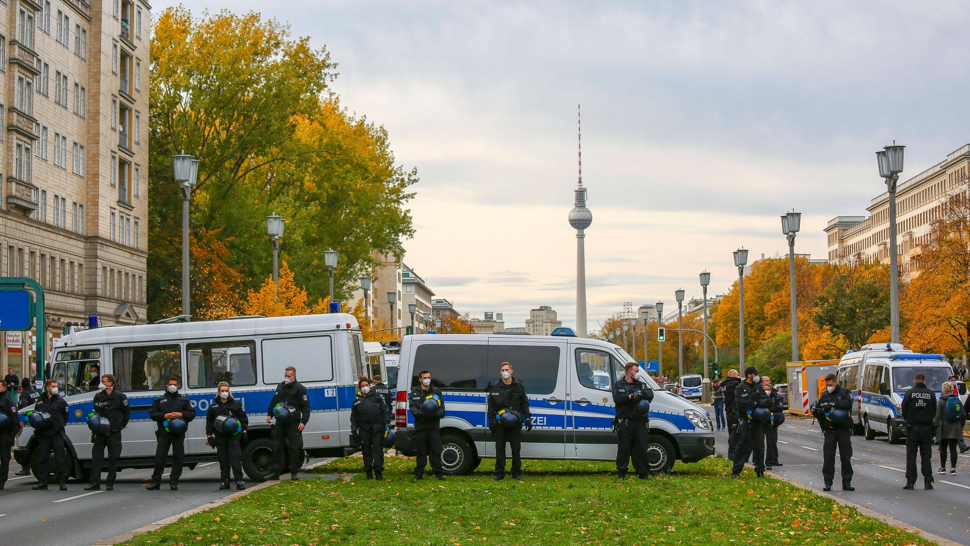 Polizisten stehen stehen vor ihren Einsatzwagen – dahinter der Fernsehturm: Teilnehmer einer Corona-Demo sind vom Alexanderplatz über die Karl-Marx-Allee gelaufen.