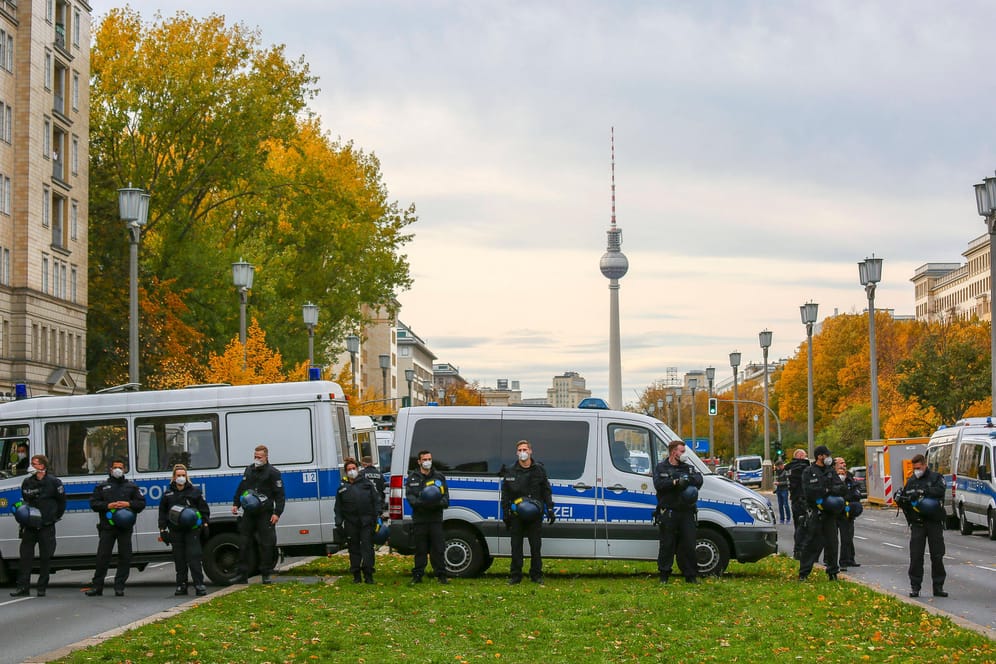 Polizisten stehen stehen vor ihren Einsatzwagen – dahinter der Fernsehturm: Teilnehmer einer Corona-Demo sind vom Alexanderplatz über die Karl-Marx-Allee gelaufen.