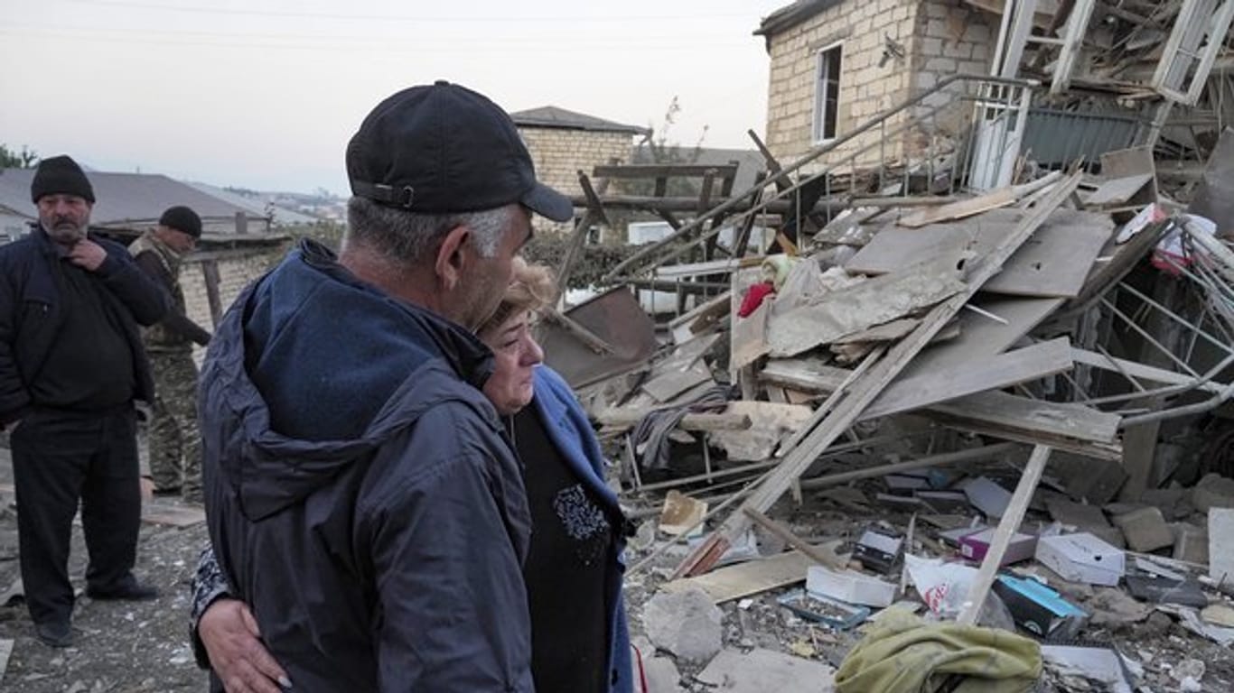 Ein Paar steht vor den Trümmern eines zerstörten Hauses in Berg-Karabach.