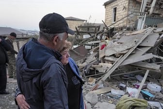 Ein Paar steht vor den Trümmern eines zerstörten Hauses in Berg-Karabach.