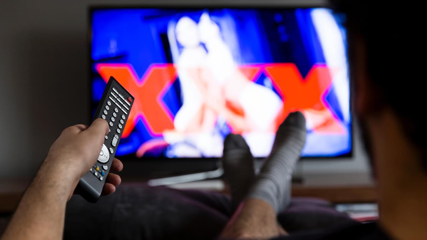 Ein Mann schaut einen Porno am Fernseher (Symbolbild): Die beliebte Seite xHamster lässt Freiwillige seine Inhalte und löschen.