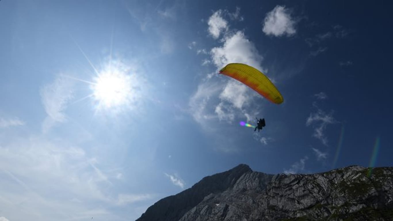 Ein Gleitschirmflieger fliegt vor blauem Himmel (Symbolbild): Gegen einen Münchener wurde Anzeige erhoben, weil er einen Gleitschirm aus dem Müll im Internet versteigert hat.