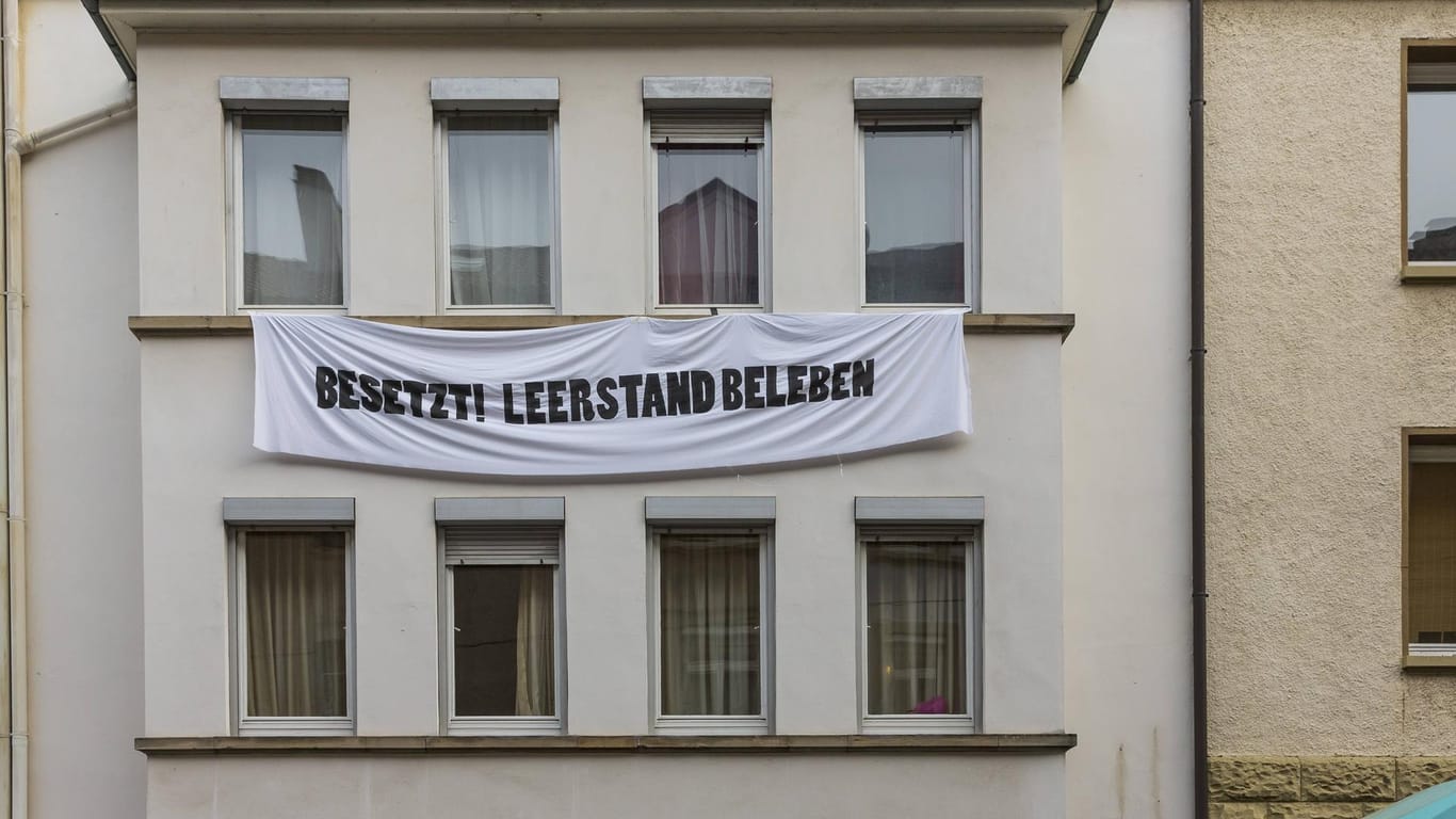 An einem Haus im Stuttgarter Süden hängt ein Banner "Besetzt! Leerstand beleben": Weil sich drei Politiker Zutritt zu einem besetzten Haus verschafft haben, stehen sie nun vor Gericht.
