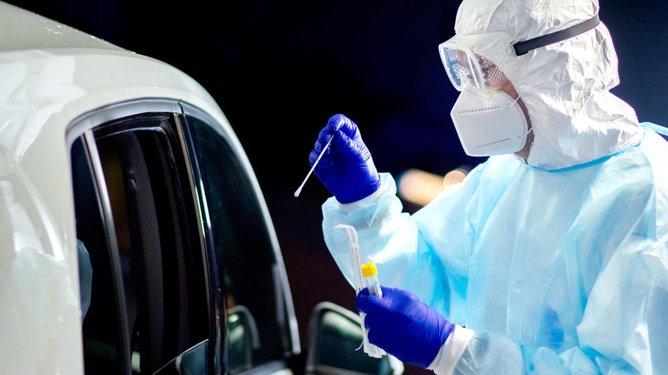 Ein Helfer nimmt in einem Corona-Drive-In-Testzentrum einen Abstrich: Das Robert Koch-Institut meldet einen neuen Rekordwert bei den Neuinfektionen.