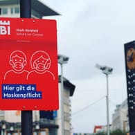 Ein Schild am Jahnplatz in Bielefeld weist auf die geltende Maskenpflicht hin: Wegen der Corona-Pandemie ist diese Maßnahme erlassen worden.