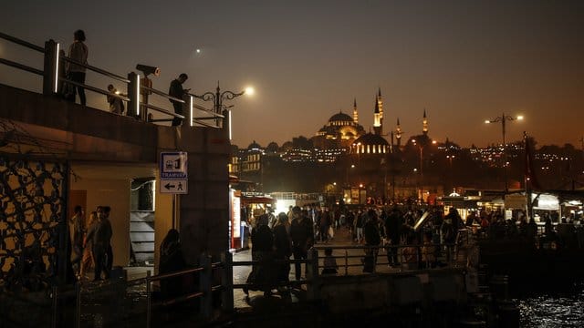 Menschen schlendern vor der Kulisse der Süleymaniye-Moschee am Ufer des Bosporus entlang. Menschen schlendern vor der Kulisse der Süleymaniye-Moschee am Ufer des Bosporus entlang.