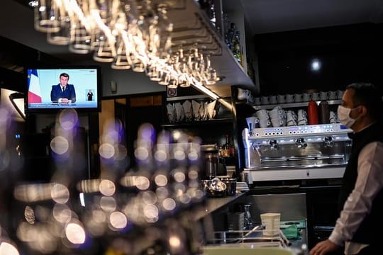 Ein Barkeeper schaut sich die Fernsehansprache von Präsident Macron in einem Café in Marseille an.
