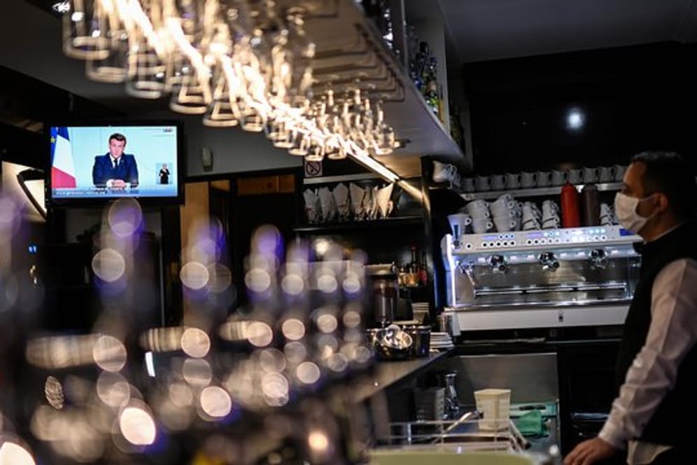 Ein Barkeeper schaut sich die Fernsehansprache von Präsident Macron in einem Café in Marseille an.