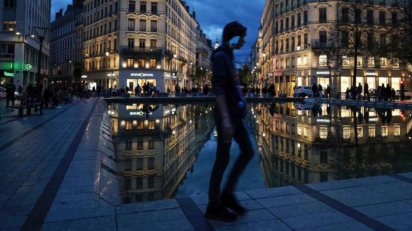 Lyon: Ein Mann, dem ein Mund-Nasen-Schutz am Ohr hängt, geht durch die Innenstadt. Mit Ausgangsbeschränkungen im ganzen Land verschärft das Land seinen Kampf gegen die zweite Welle der Corona-Pandemie.