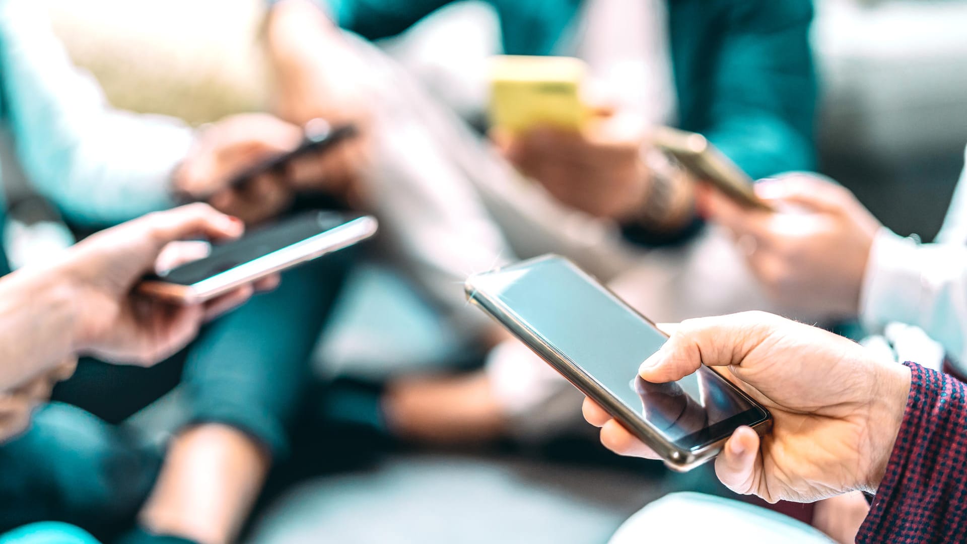 Eine Gruppe junger Menschen spielt mit dem Smartphone: Wenn ein Nutzer einen Hotspot aufmacht, können andere von seinem Datenvolumen zehren.