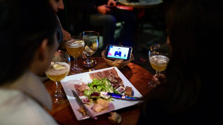 Paris: Macron ist auf dem Bildschirm eines Smartphones in einem Café zu sehen, während er sich in einer TV-Ansprache an die Nation wendet.