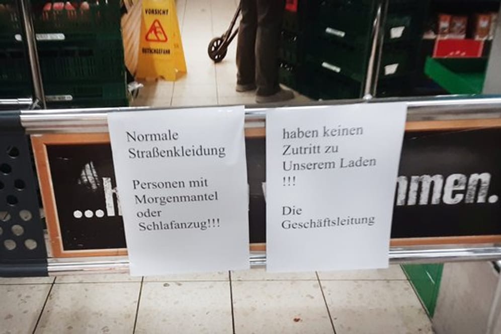 Hinweiszettel machen die Kundschaft in dem Duisburger Supermarkt auf die nun geltende Kleiderordnung aufmerksam.