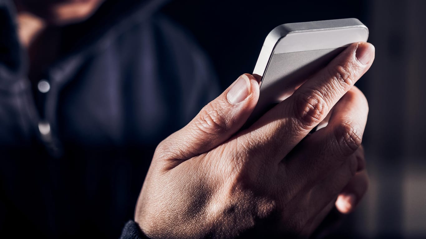 Ein Mann hält ein iPhone in der Hand (Symbolbild): Apple warnt vor Betrugsnachrichten an iPhone-Nutzer.