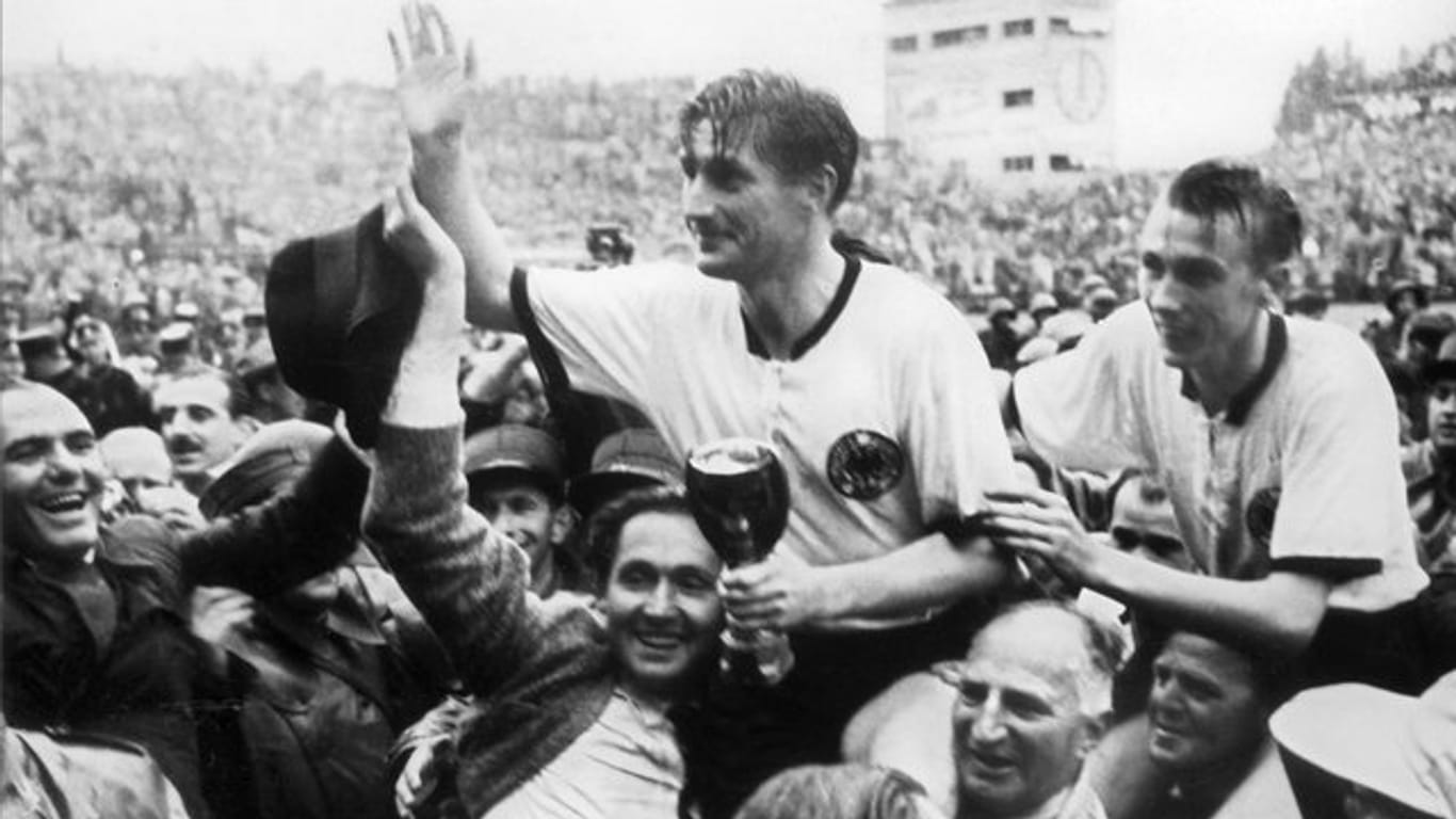 Der deutsche Stürmer und Kapitän Fritz Walter (M, oben) und sein Lauterer Teamgefährte Horst Eckel (r) werden nach dem Triumph im Fußball-WM-Finale im Berner Wankdorfstadion von begeisterten Anhängern vom Spielfeld getragen.