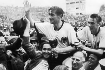 Der deutsche Stürmer und Kapitän Fritz Walter (M, oben) und sein Lauterer Teamgefährte Horst Eckel (r) werden nach dem Triumph im Fußball-WM-Finale im Berner Wankdorfstadion von begeisterten Anhängern vom Spielfeld getragen.