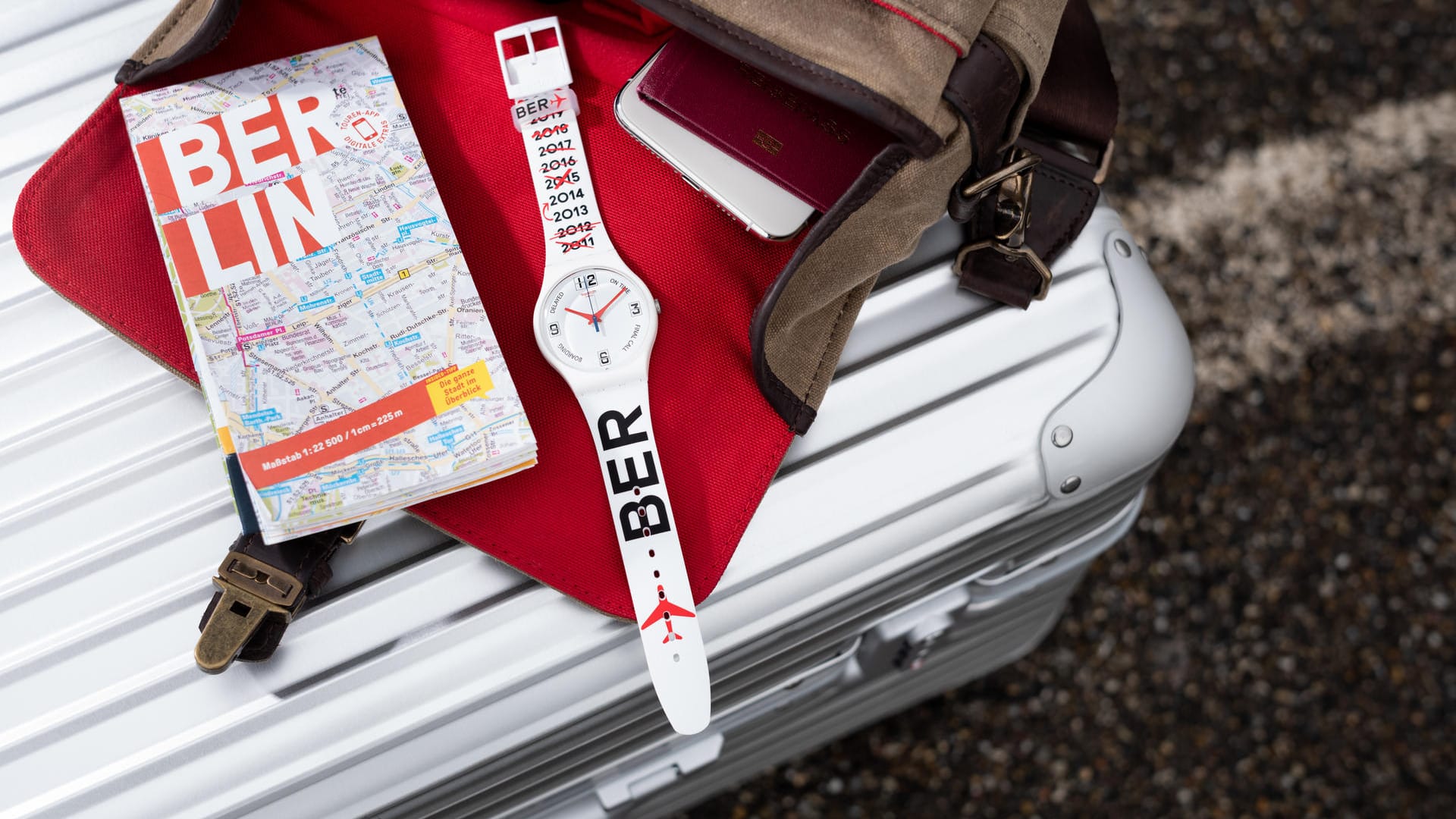 Eine Uhr liegt neben einem Berlin-Stadtplan: Der Uhrenhersteller Swatch bringt zur BER-Eröffnung eine Sonderedition heraus.