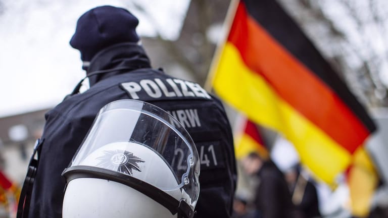 Polizist neben einer Deutschlandflagge: Die Zahl der rechtsextremistischen Gefährder ist zuletzt angestiegen. (Symbolbild)