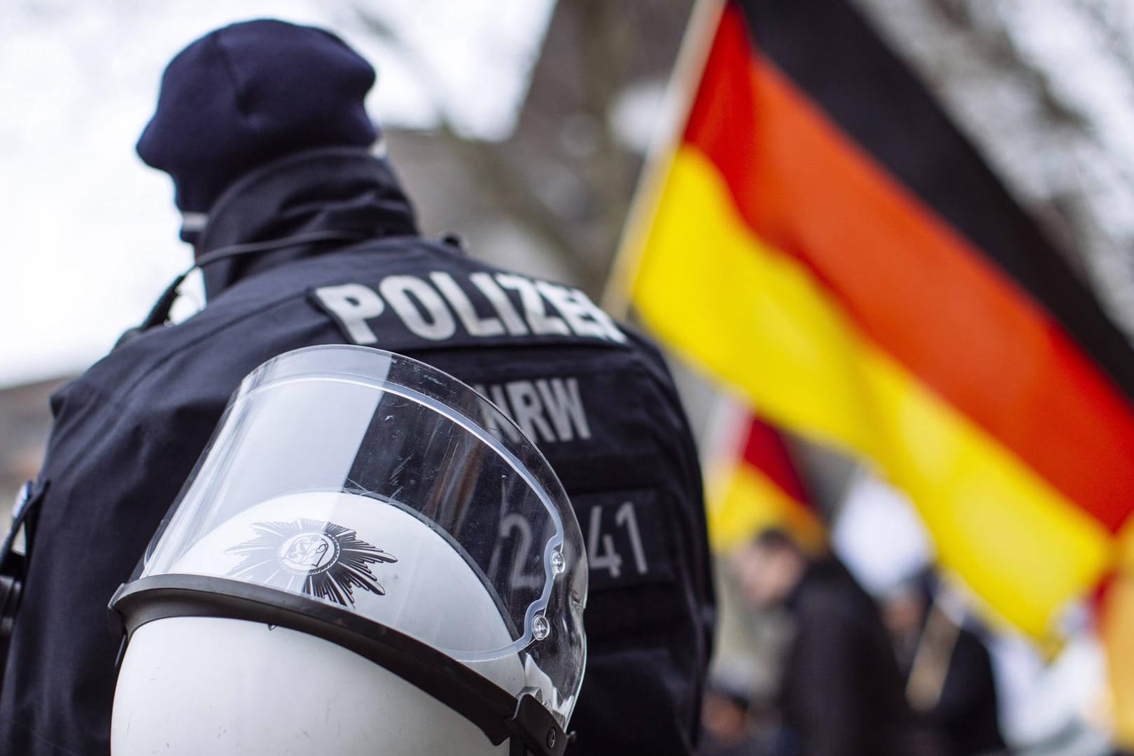 Polizist neben einer Deutschlandflagge: Die Zahl der rechtsextremistischen Gefährder ist zuletzt angestiegen. (Symbolbild)