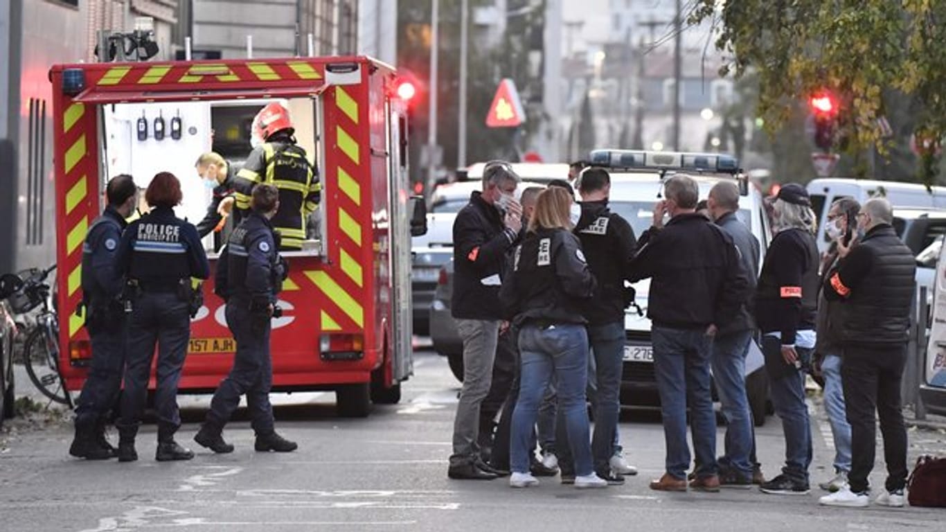 Rettungskräfte und Beamte der Polizei stehen am Tatort, an dem ein griechisch-orthodoxer Priester angeschossen wurde.