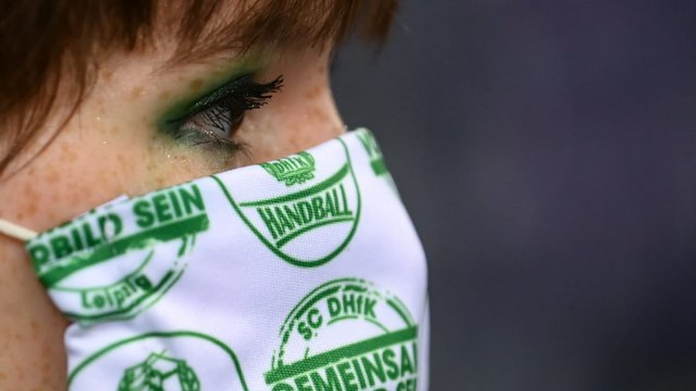 Eine junge Frau trägt eine Maske mit dem Logo des Vereins.