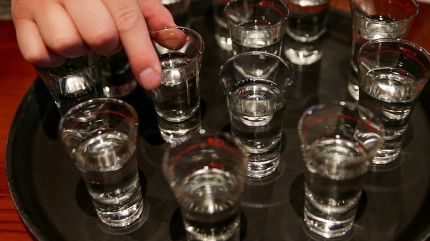 Eine Hand greift nach einem der gefüllten Schnapsgläser (Symbolbild): 7,9 Millionen Deutsche konsumieren laut Suchtbericht Alkohol "in gesundheitlich riskanter Weise".